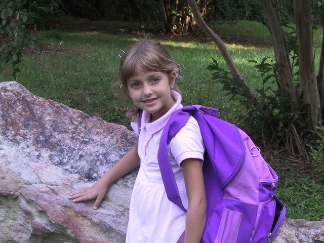 malá holčička v bílých šatech a s fialovým batohem